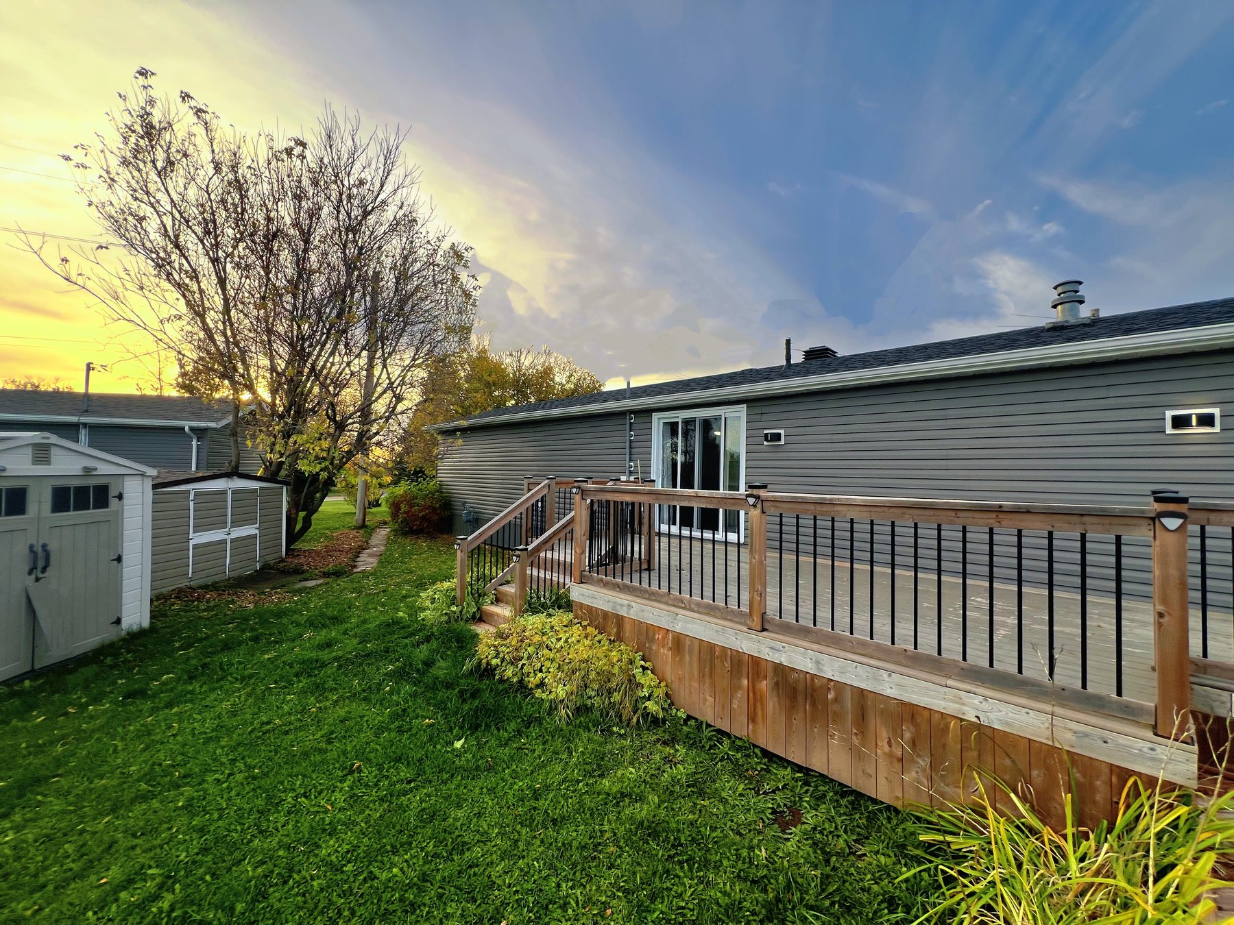 A mobile home with a deck and yard at Cochrane Mobile Home Park